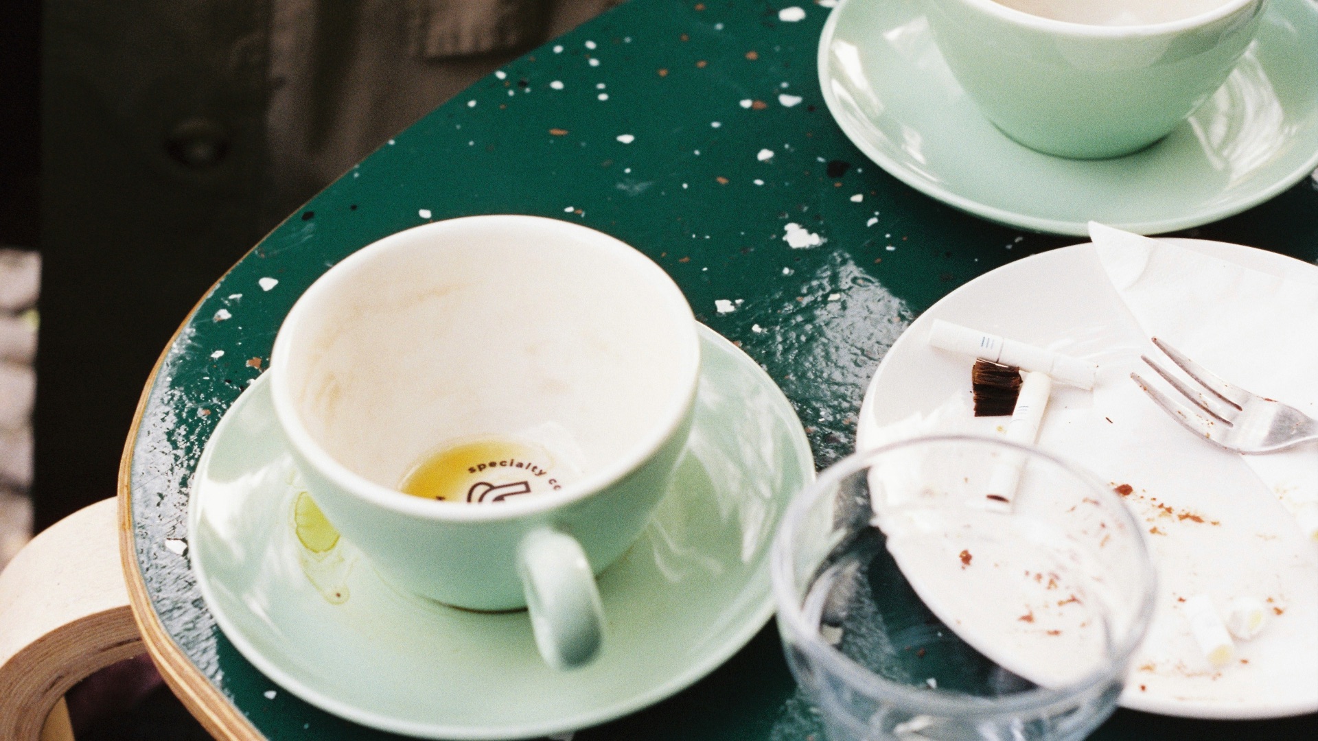 Two empty teacups and a plate on a green table