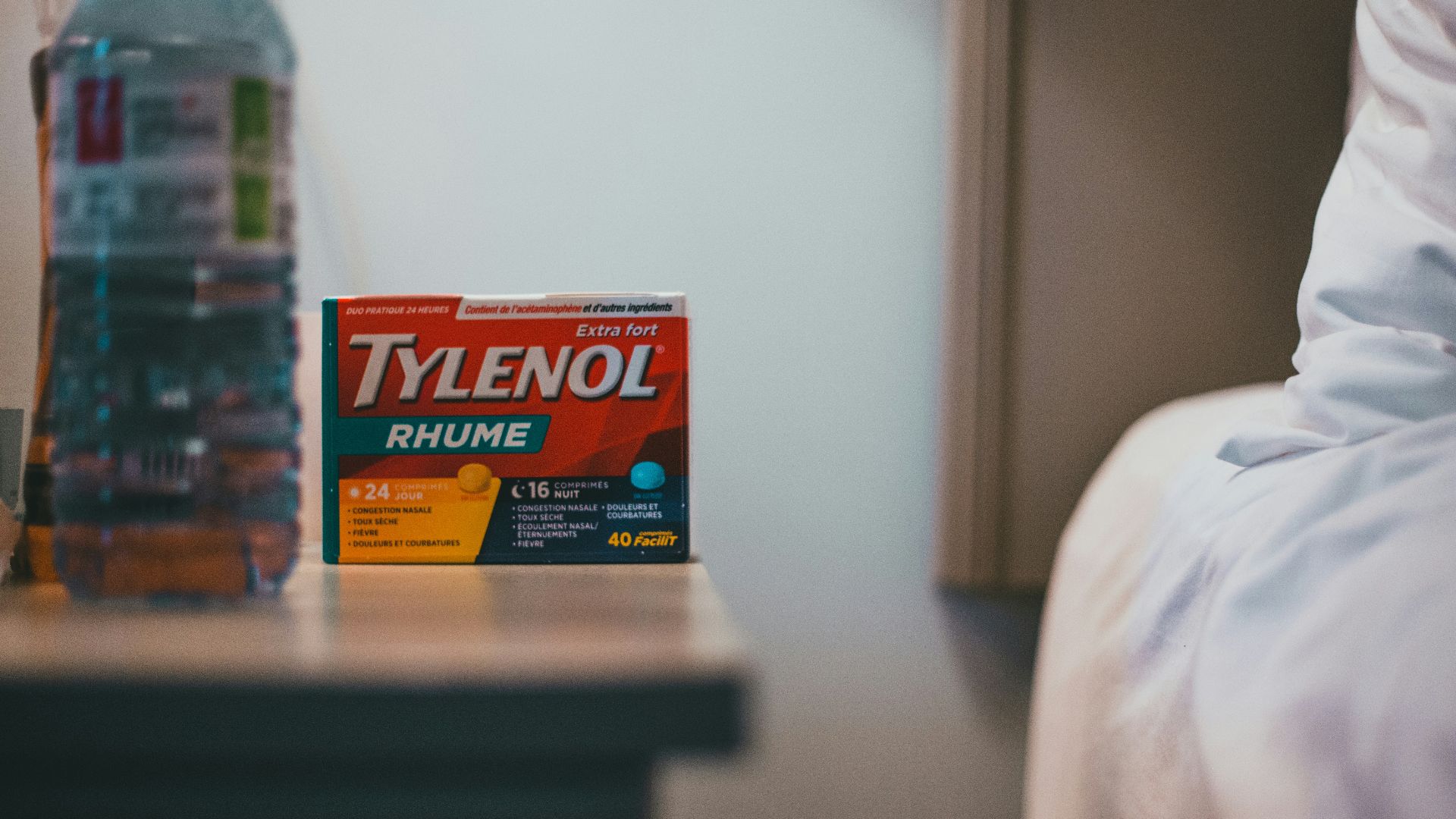 a bottle of tylenol next to a bed