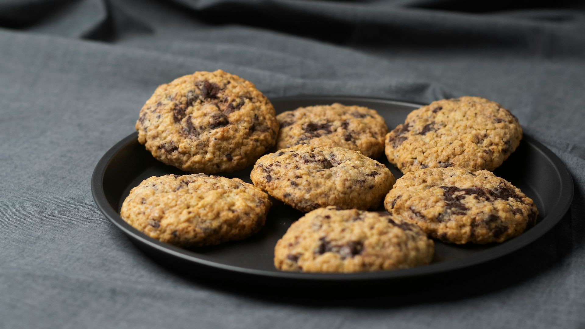 a plate of chocolate chip cookies on a gray cloth