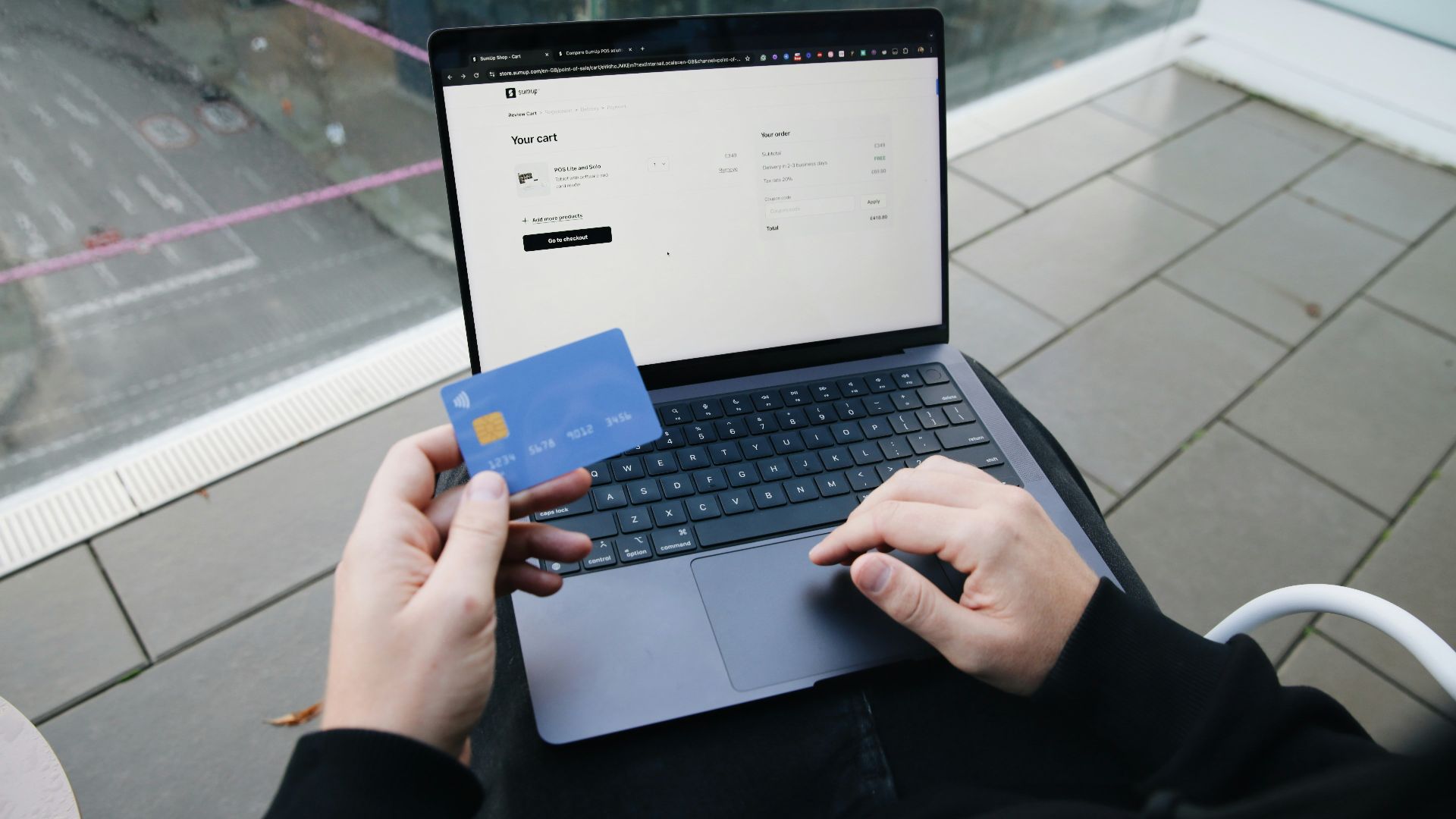 A person sitting in a chair with a laptop and a credit card