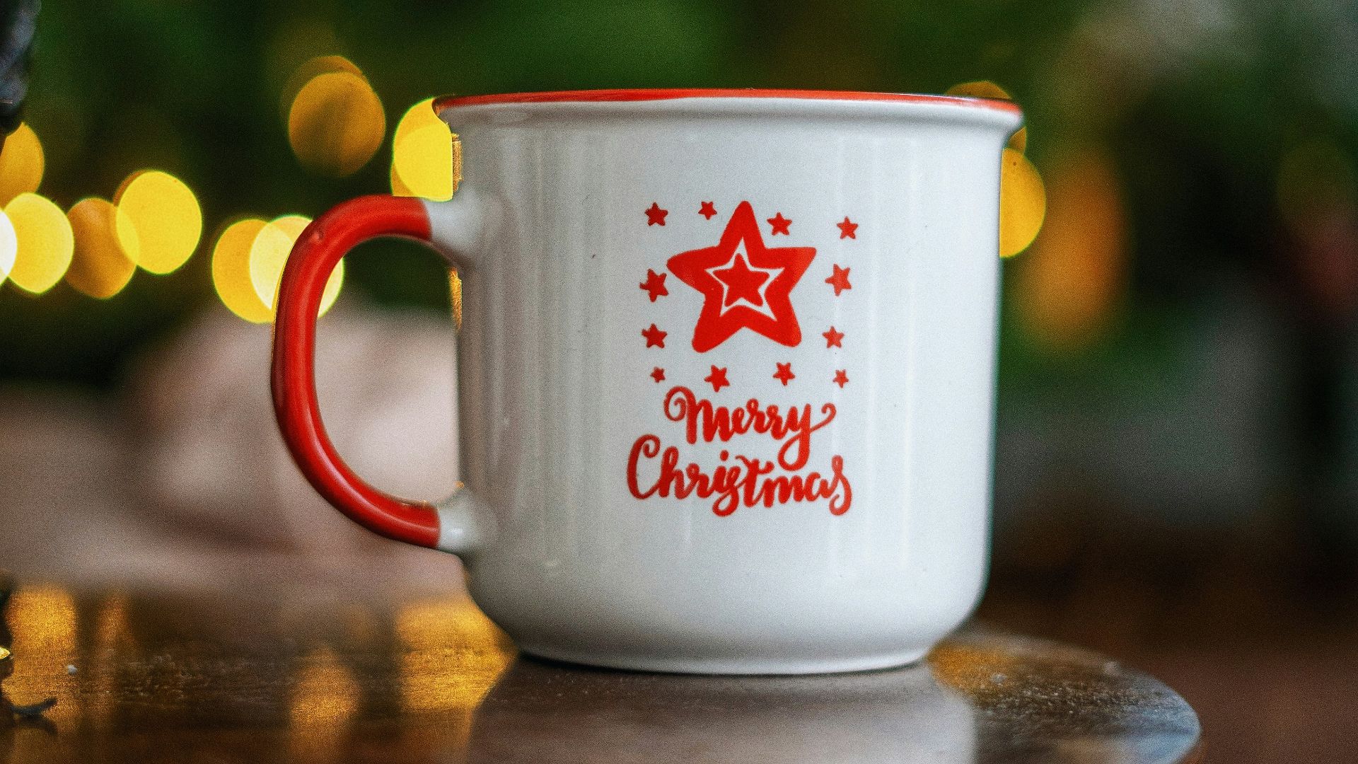 white and red ceramic mug on brown wooden table