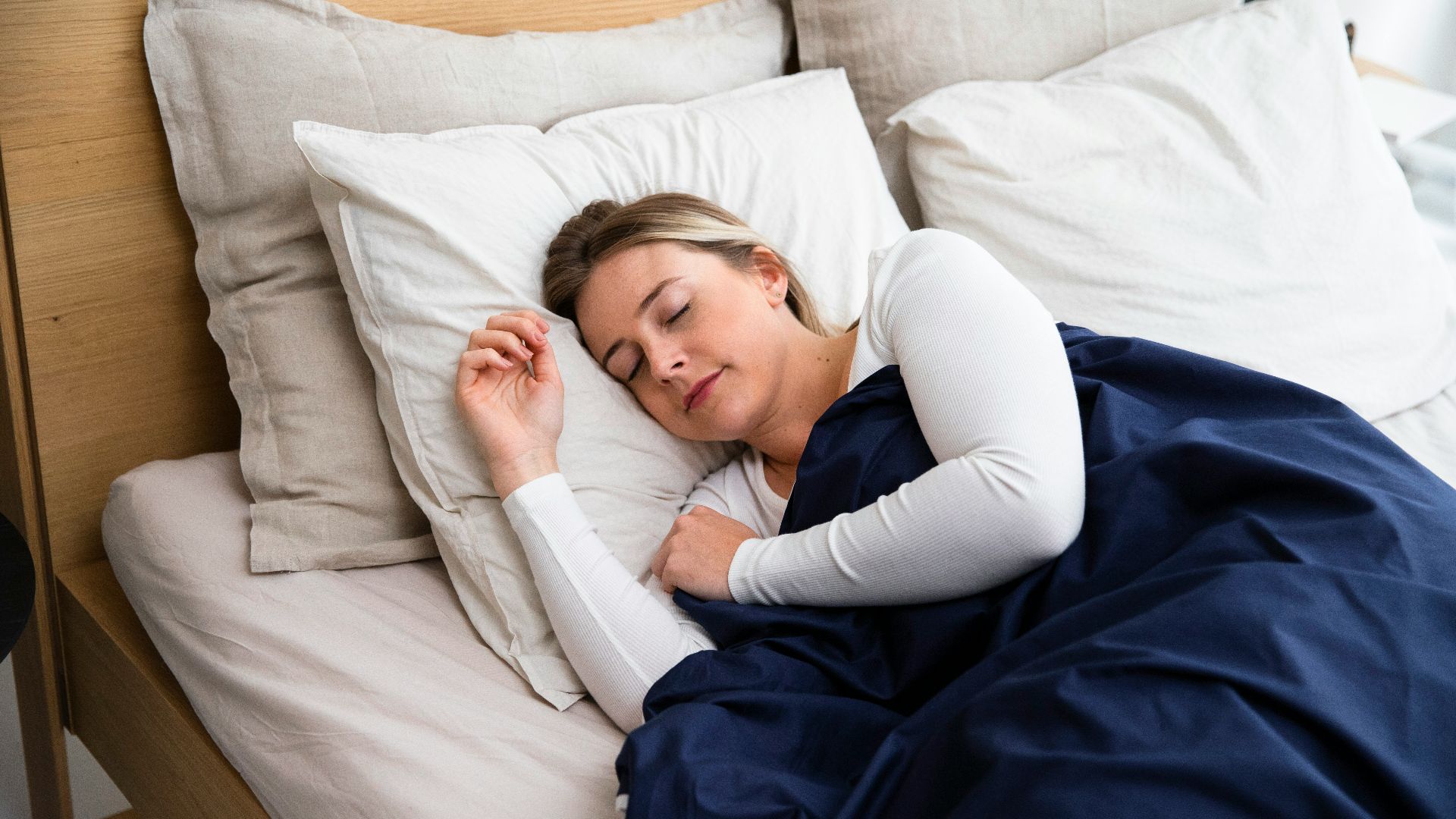 a woman sleeping on a bed with a blue blanket
