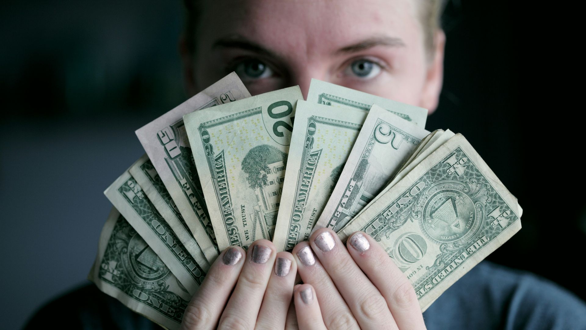 person holding fan of U.S. dollars banknote
