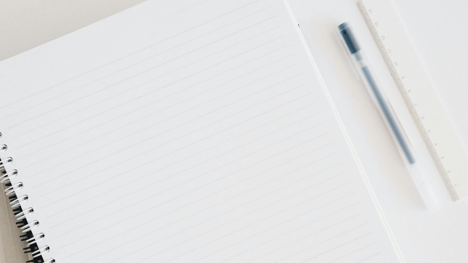 empty spiral notebook near keyboard and pen