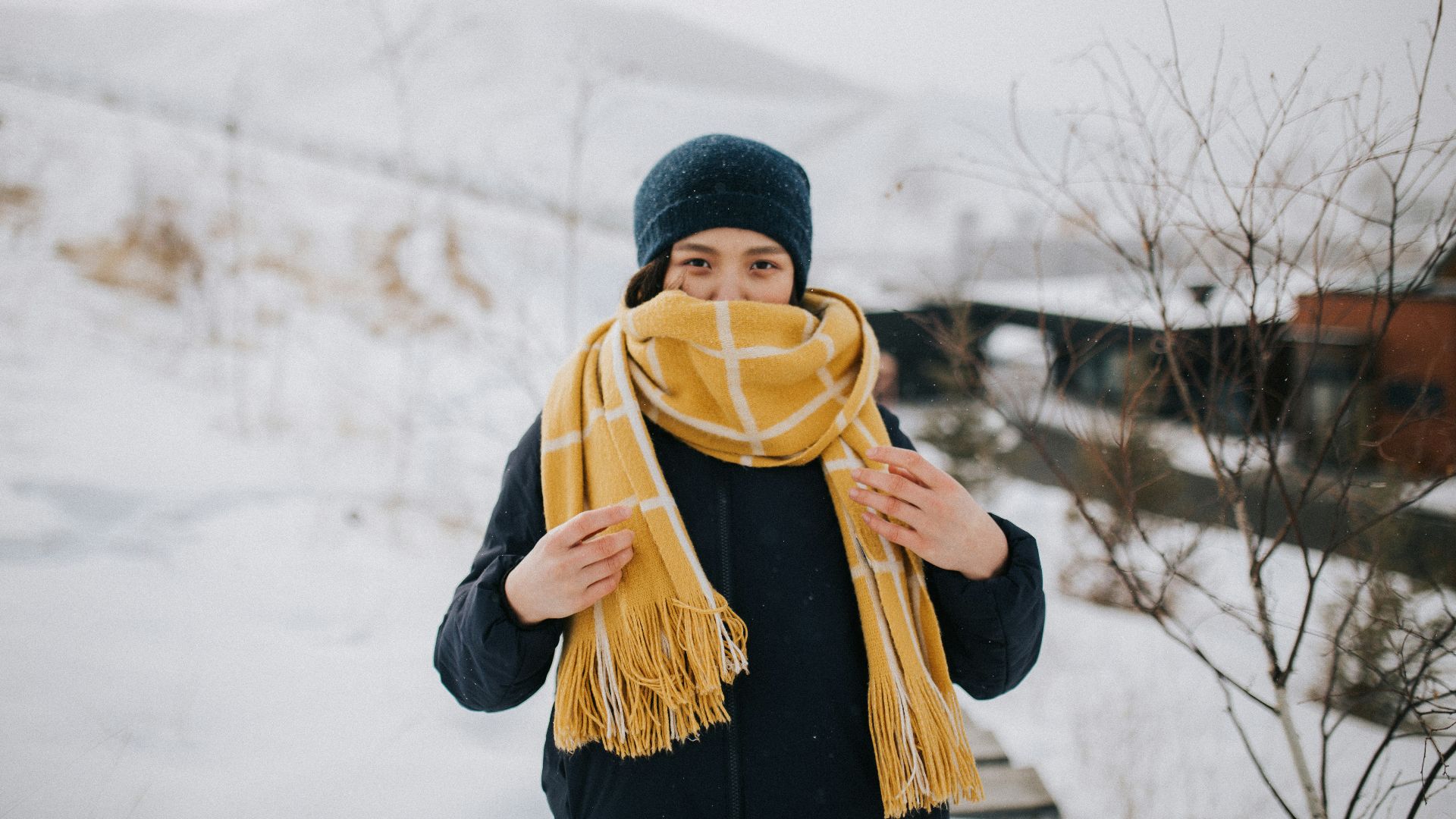 woman in black knit cap and black jacket standing on snow covered ground during daytime