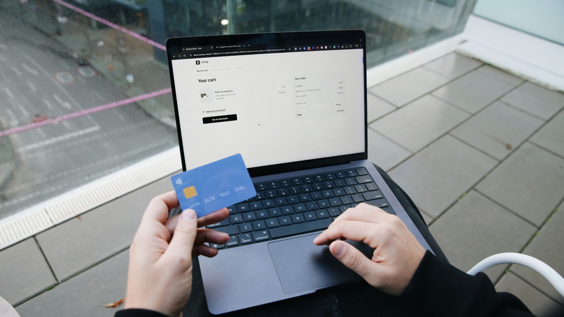 A person sitting in a chair with a laptop and a credit card