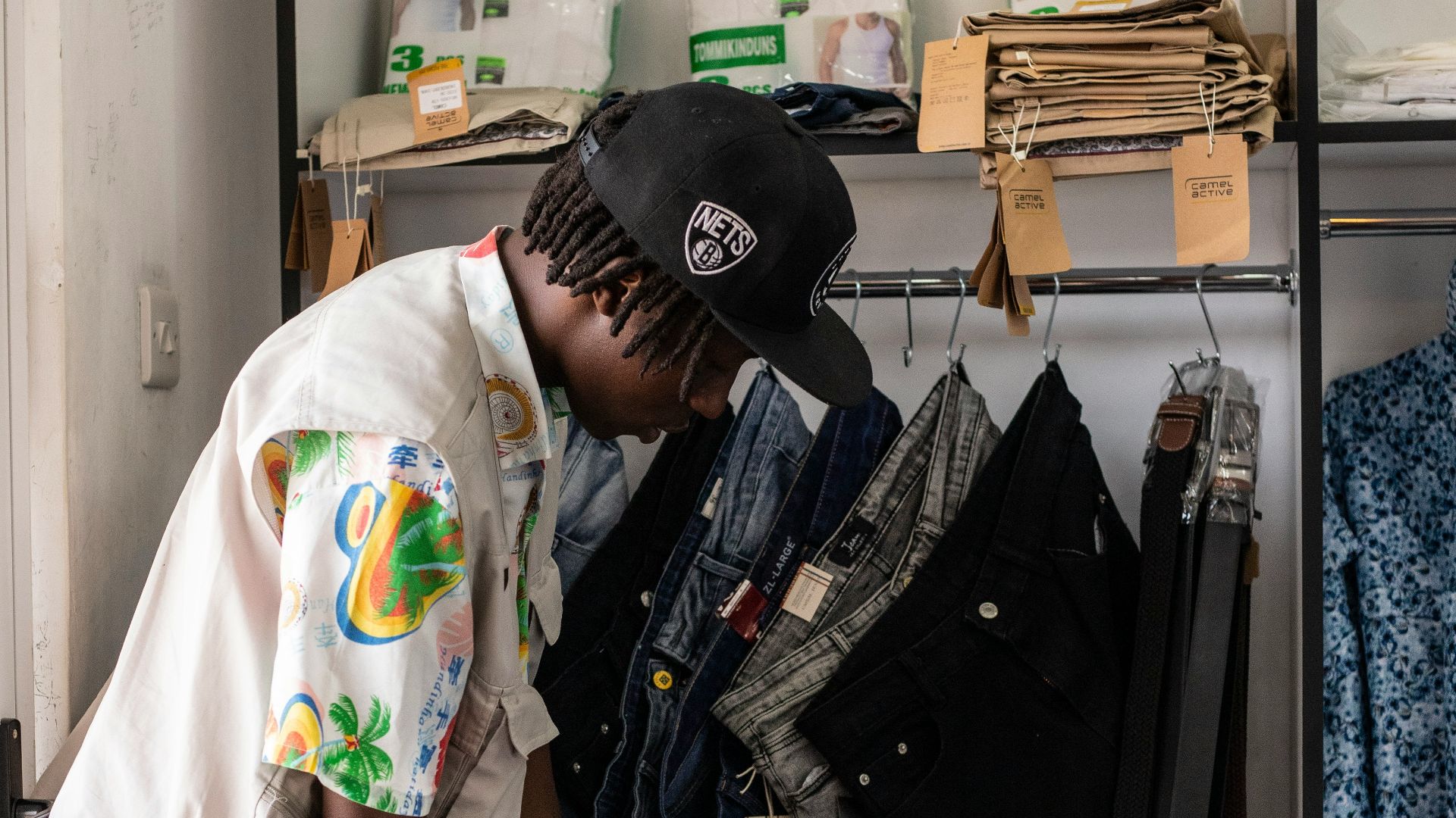 A man standing in front of a closet filled with clothes