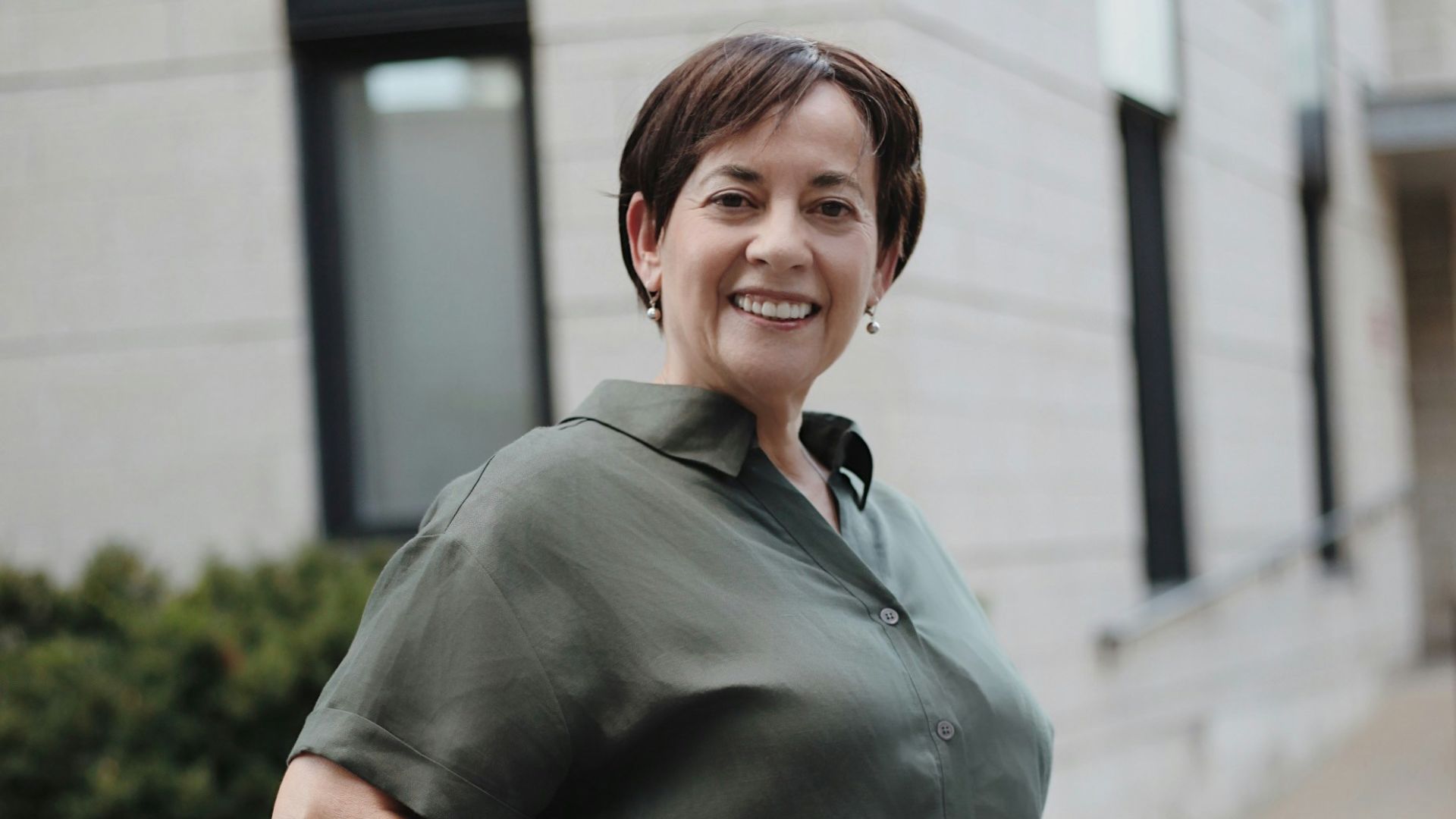 man in green button up t-shirt and white pants standing on road during daytime