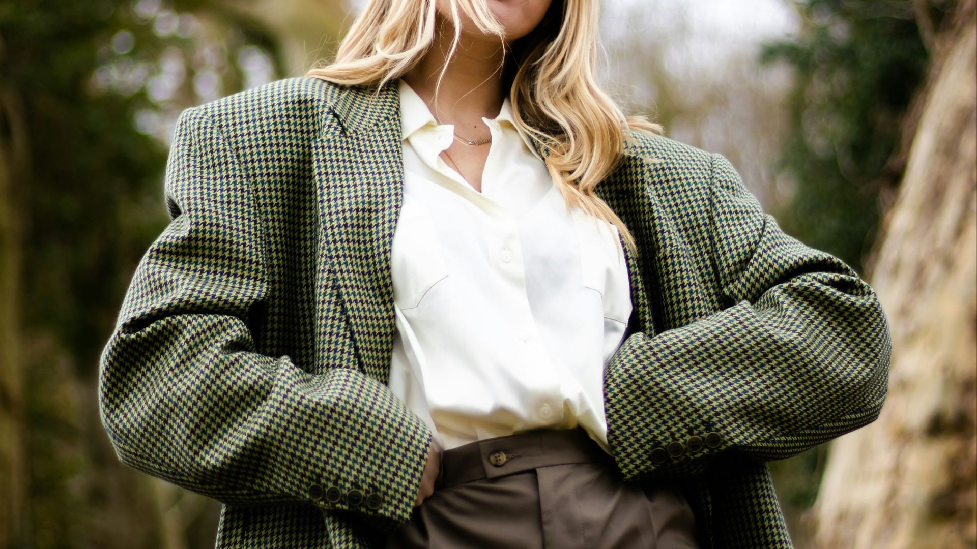 woman in gray and white polka dot blazer standing and smiling