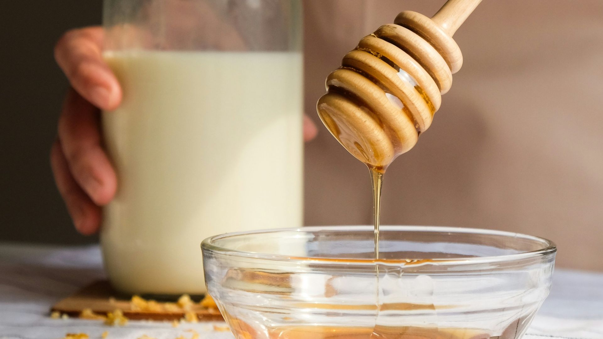 person holding clear glass jar with white liquid