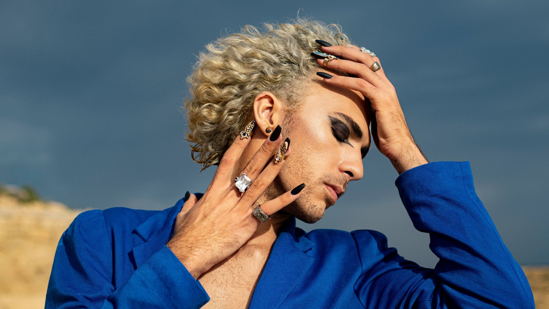 a man in a blue shirt holding his hands to his head