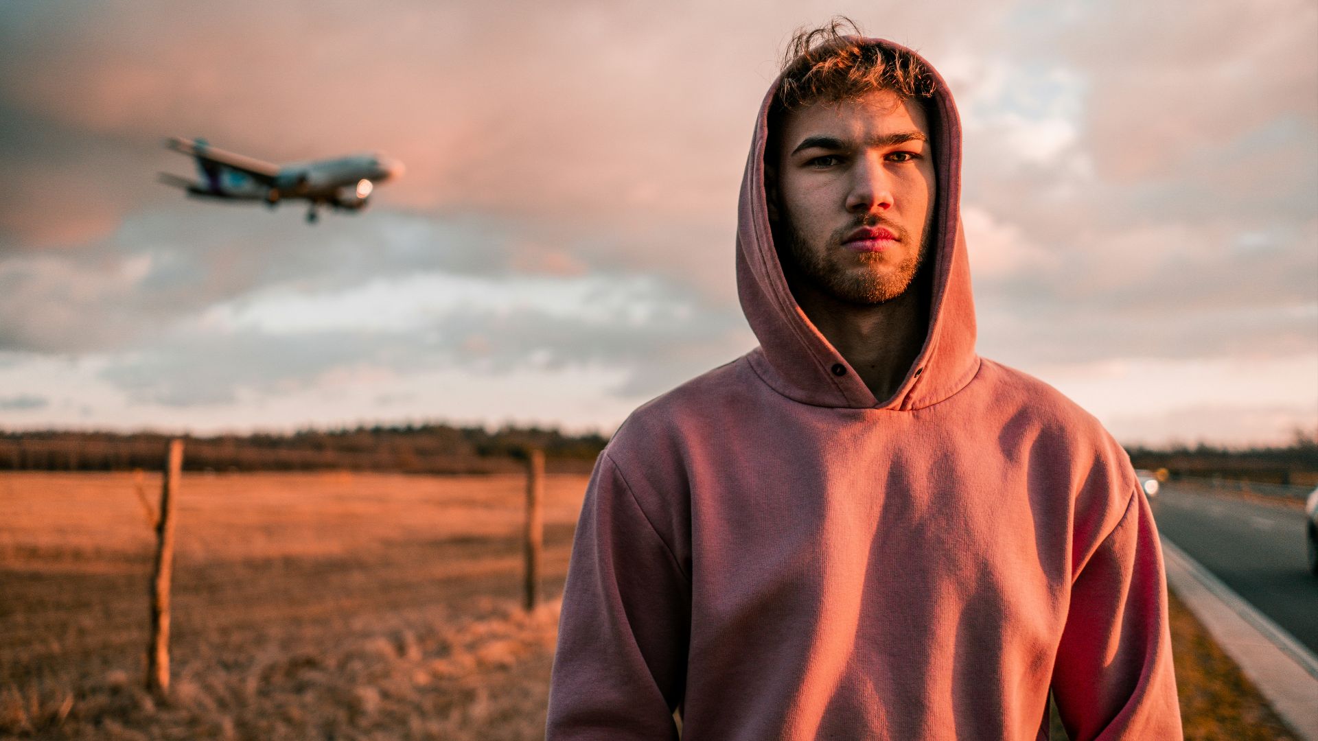 man in brown hoodie standing on brown field during daytime