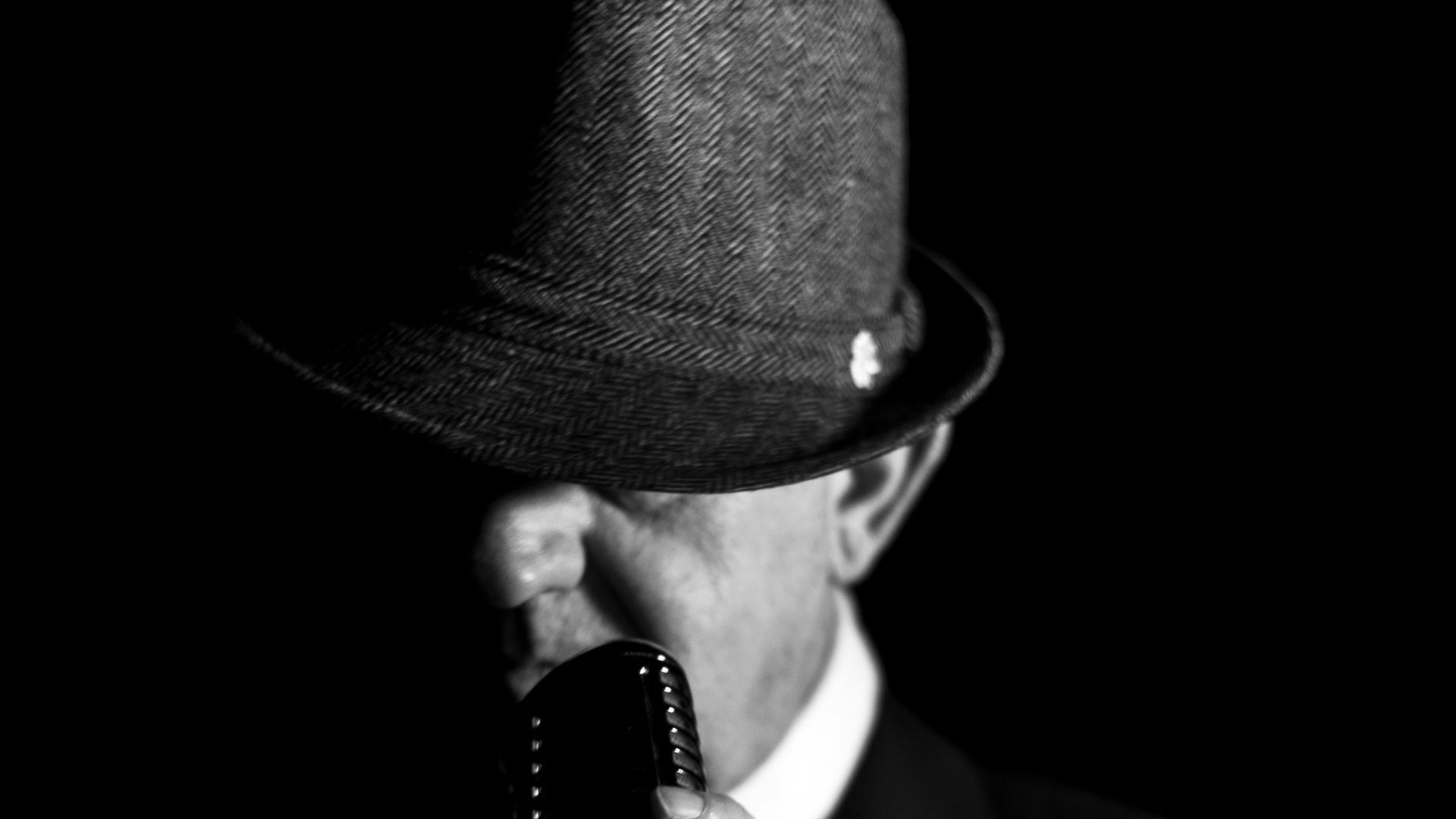 a man in a suit and hat holding a cell phone