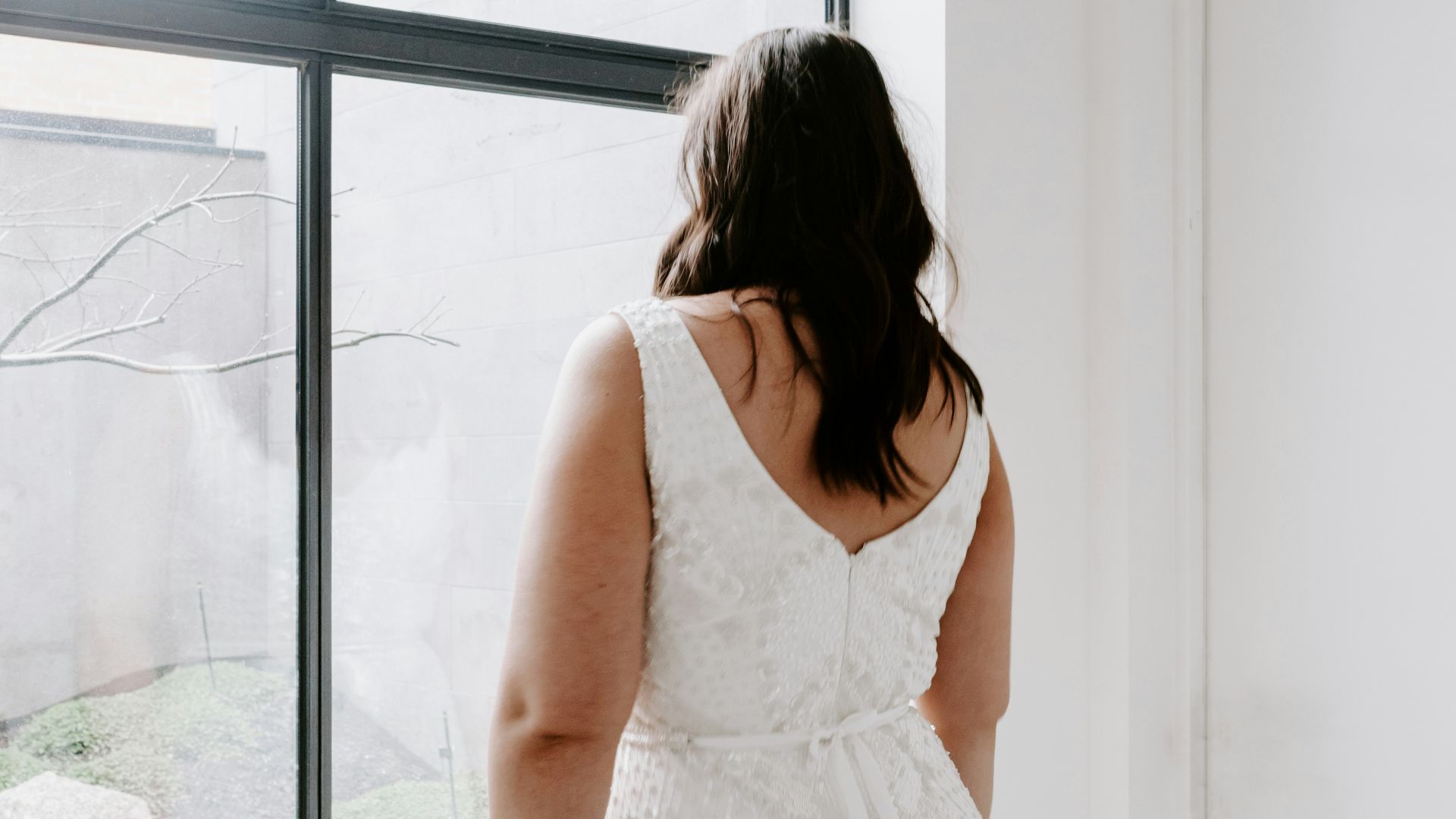 woman in white sleeveless dress standing near window