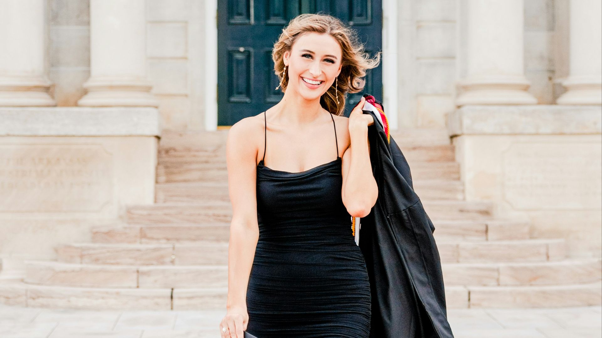 a woman in a black dress is walking down the street