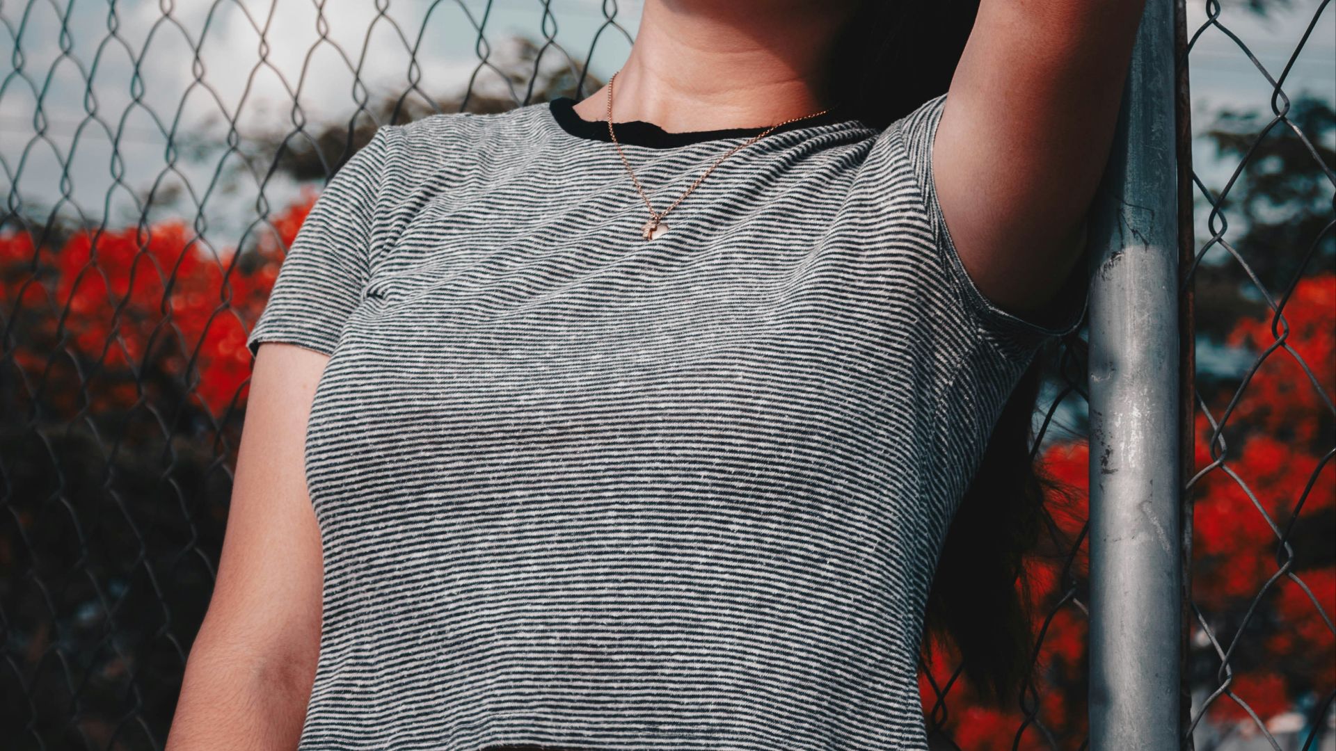 woman wearing gray crew-neck crop top holding gray fence