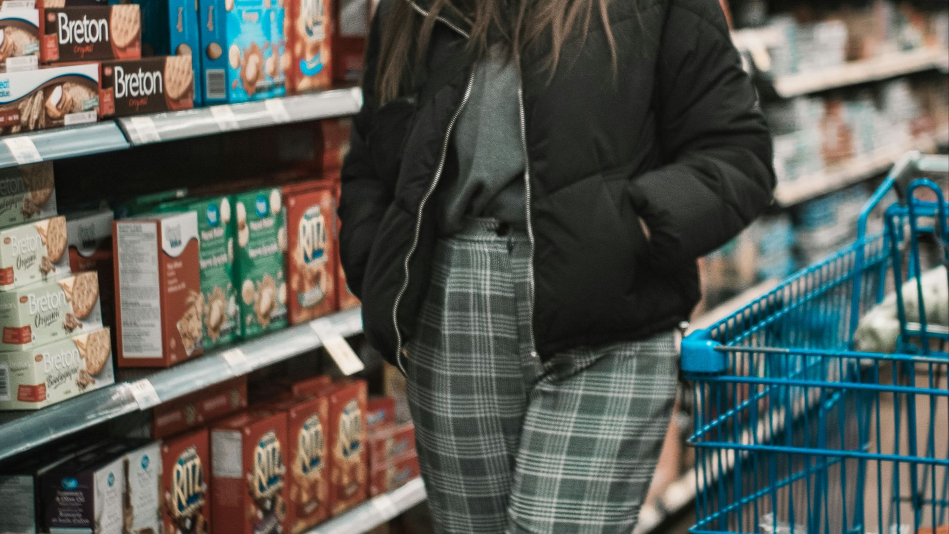 woman standing near shopping cart and groceries inside warehouse