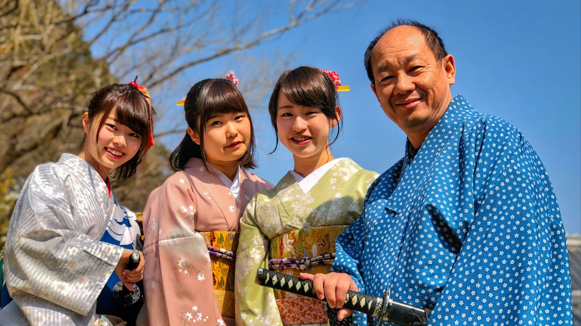 three women wearing kimono beside man holding katana sword