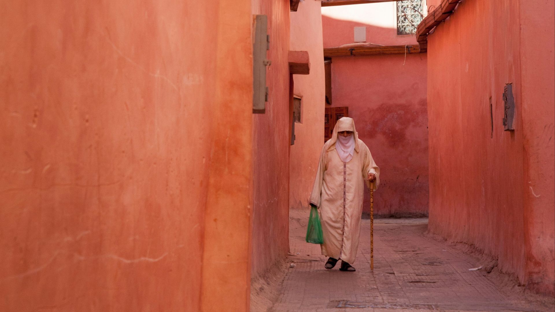 a woman walking down a narrow alley way