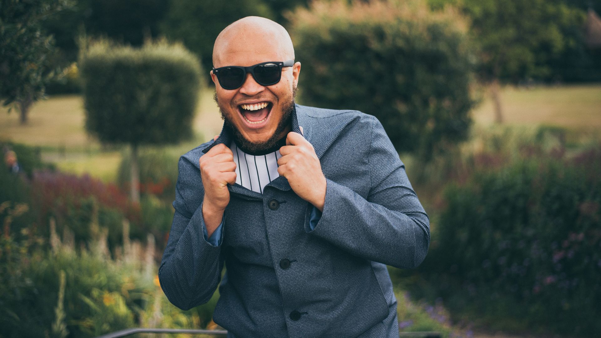 man in gray suit jacket wearing black sunglasses