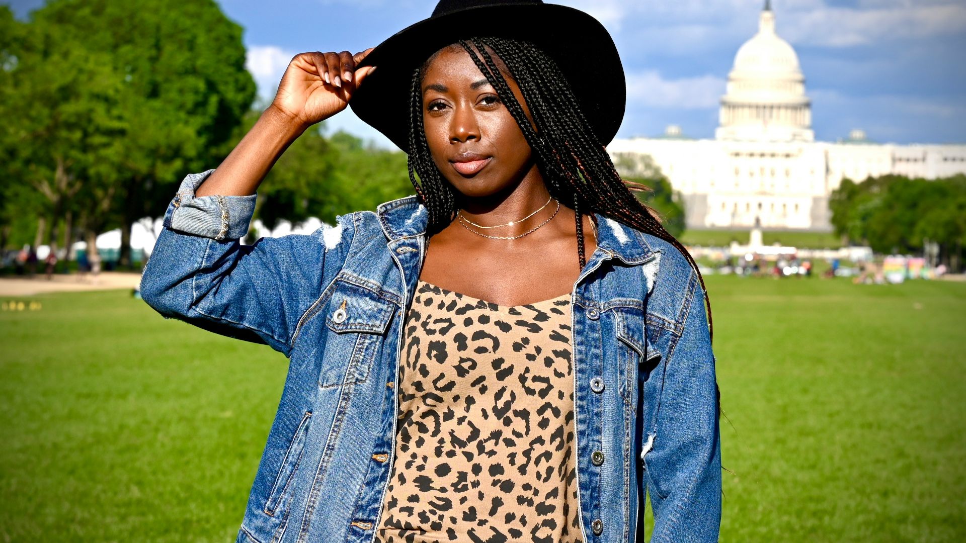 woman in blue denim jacket standing on green grass field during daytime