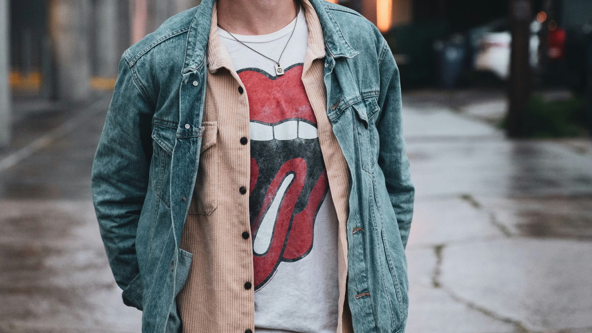 man in gray jacket standing on sidewalk during daytime