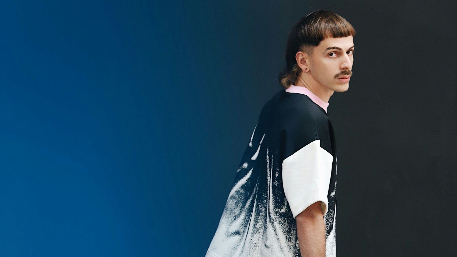 a man standing in front of a blue wall