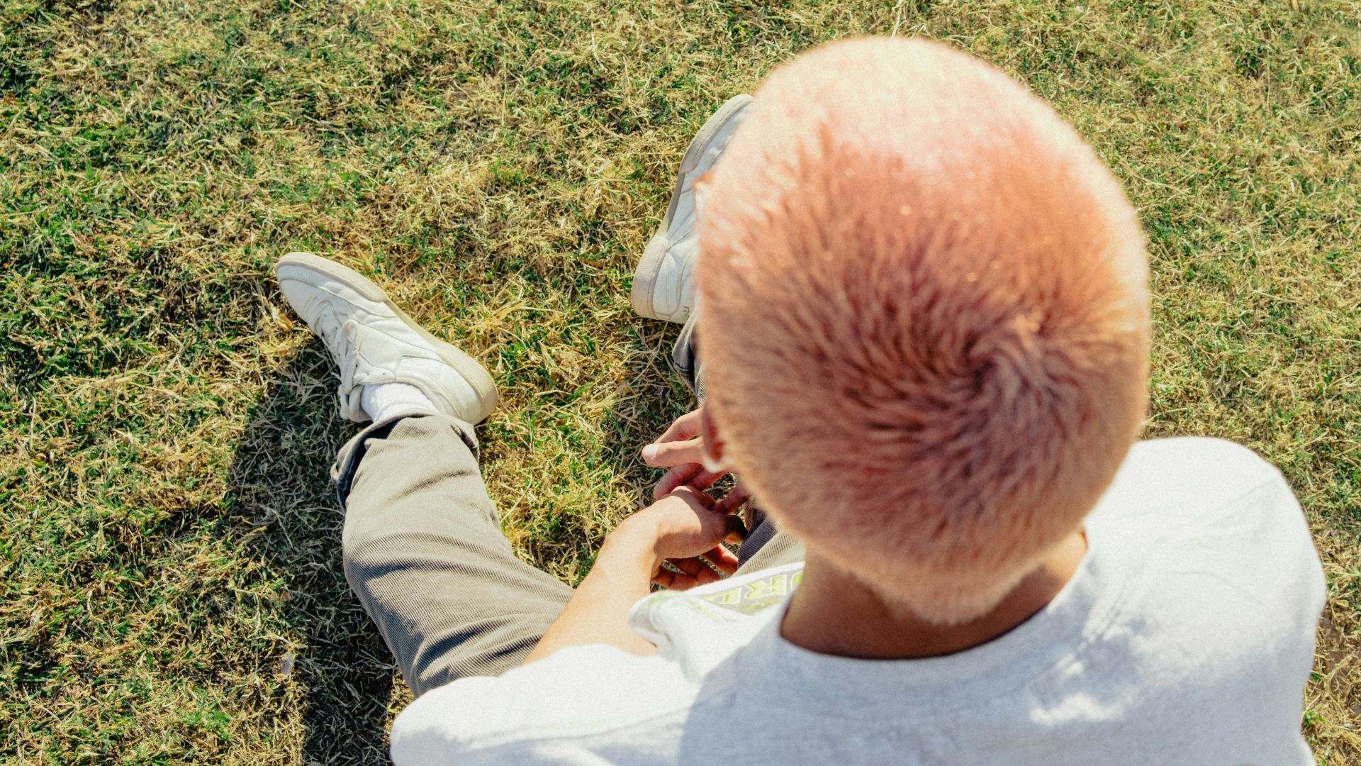 man in white shirt sitting on green grass field