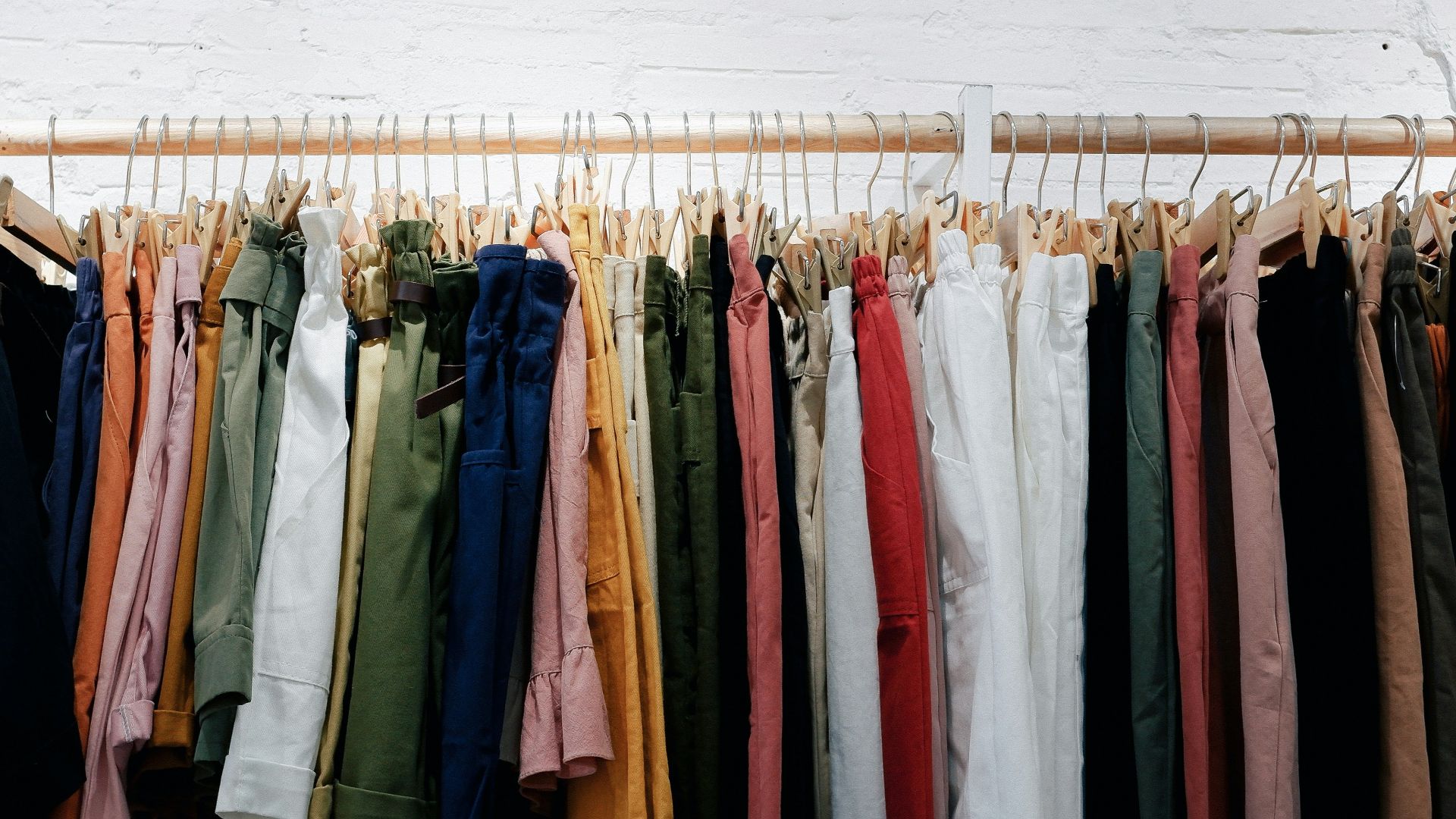 assorted-color clothes lot hanging on wooden wall rack