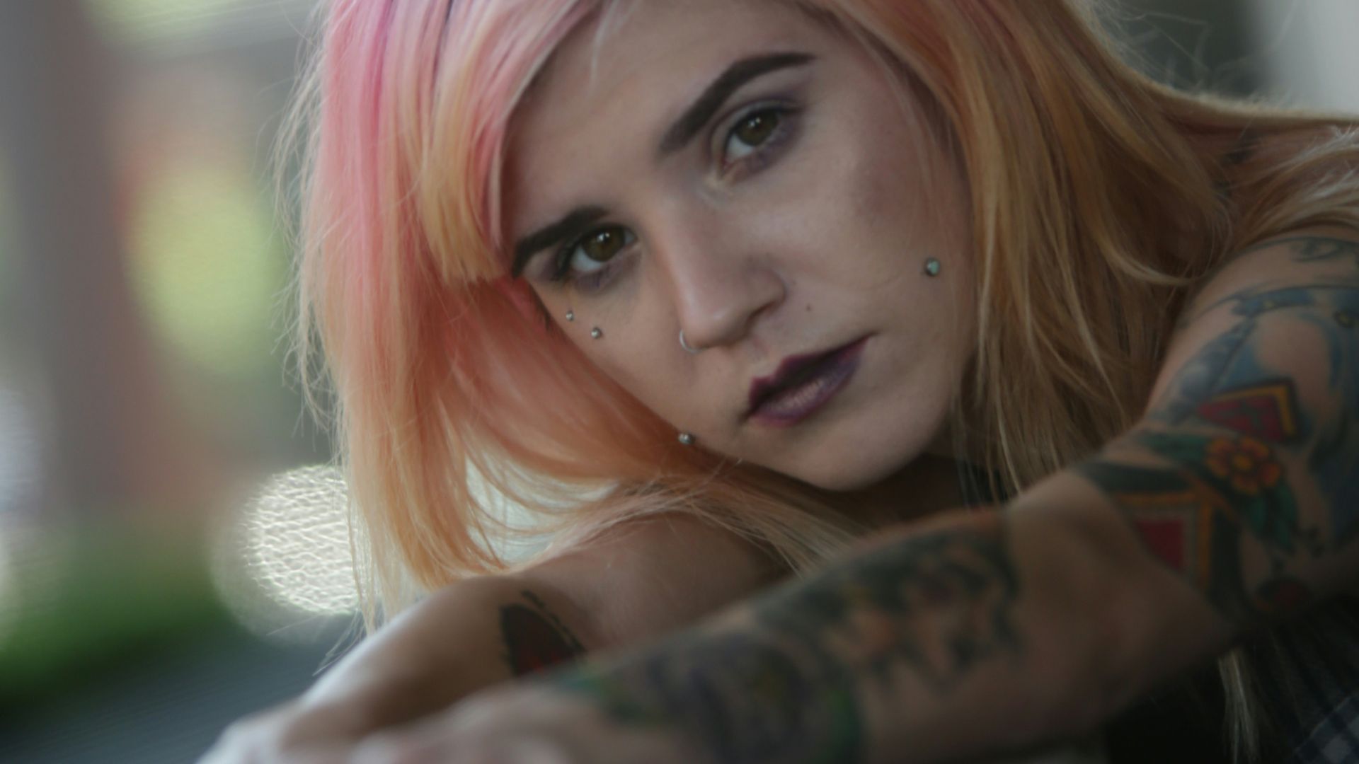 a woman with pink hair leaning on a wall