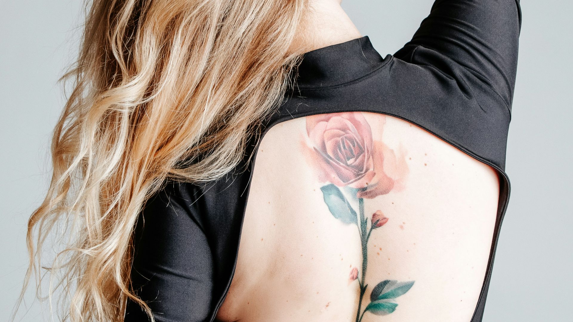 woman with red and green rose tattoo on her right arm