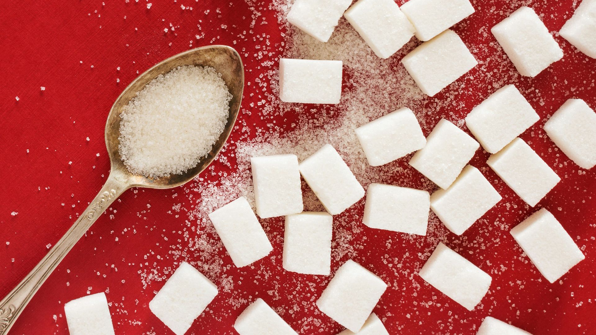 sugar cubes and a spoon on a red surface