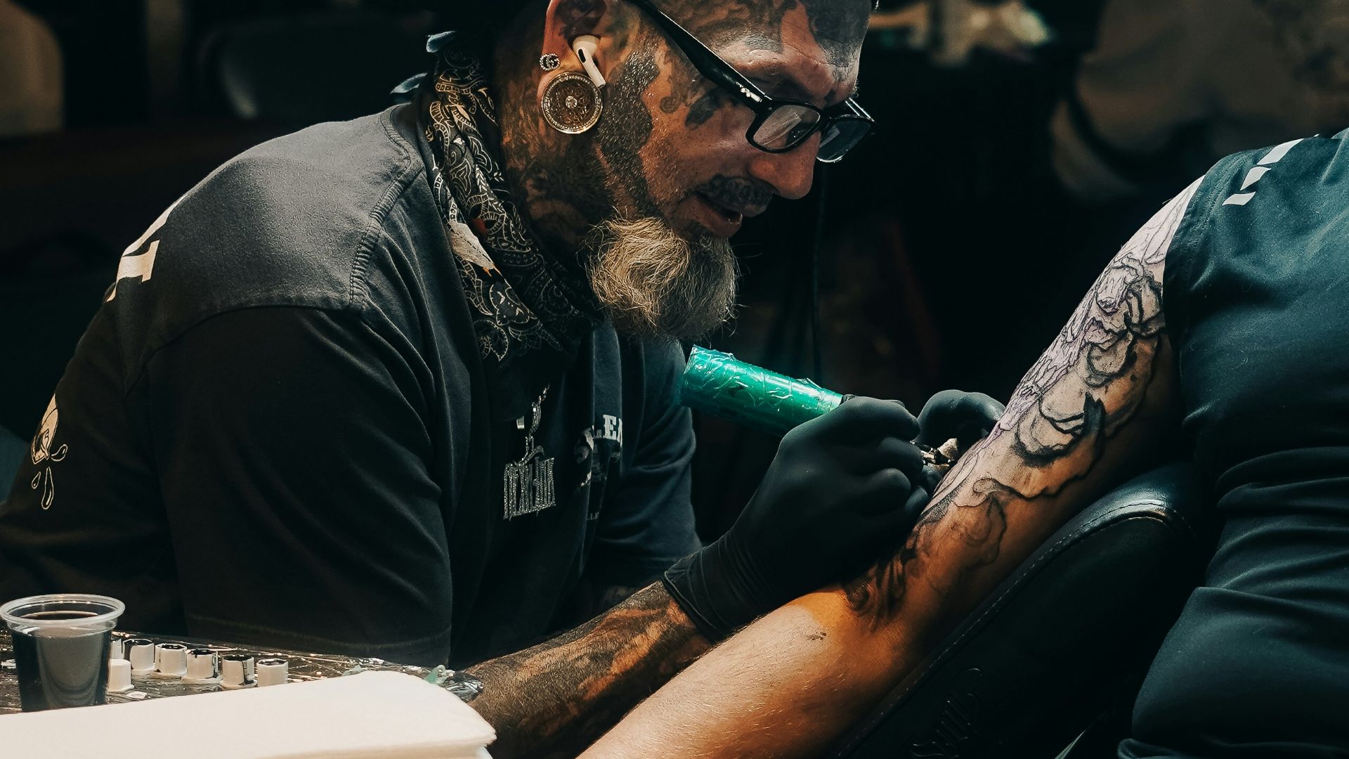 A tattoo artist is working on a client's arm.