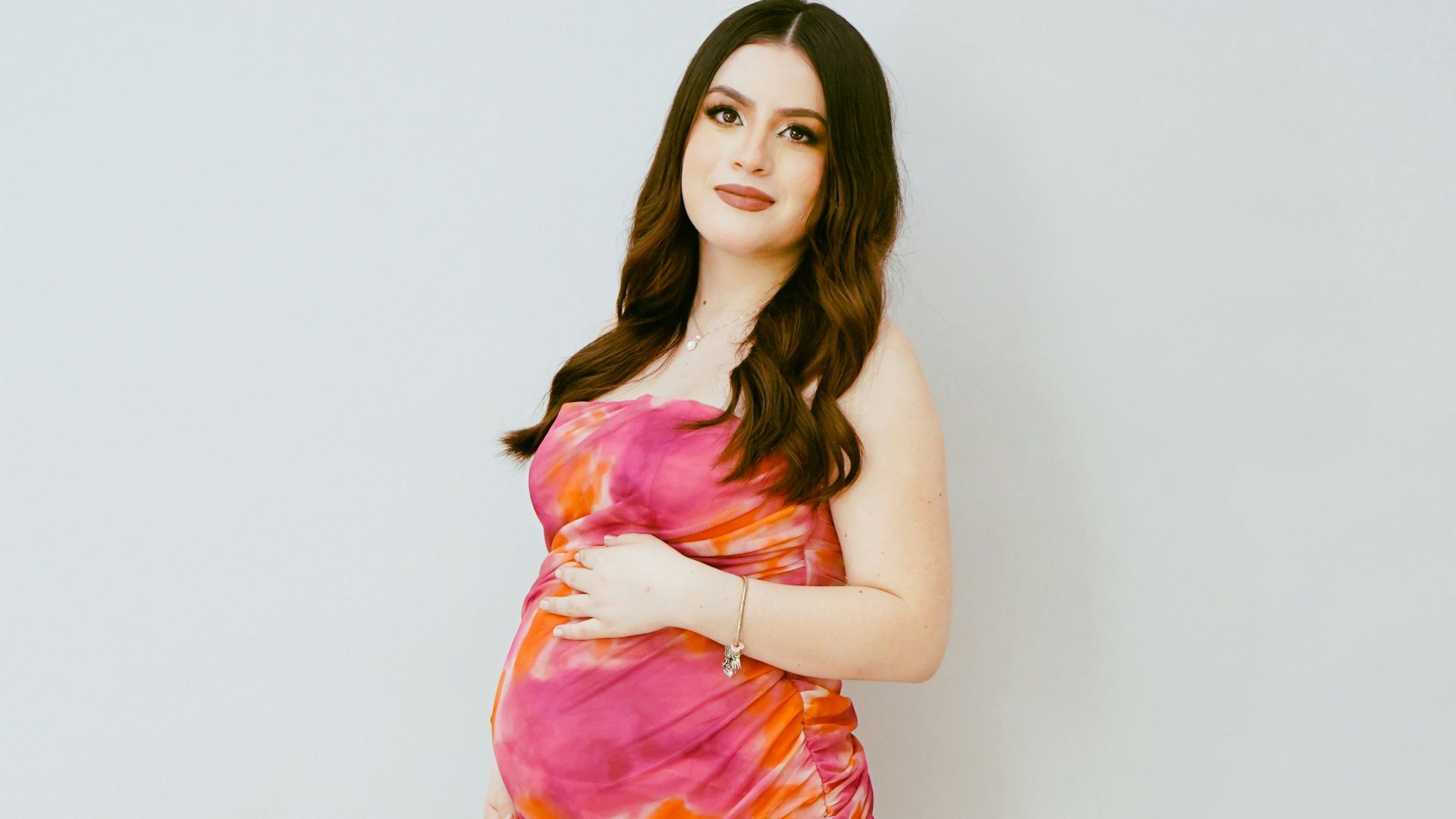 a pregnant woman in a pink and orange dress