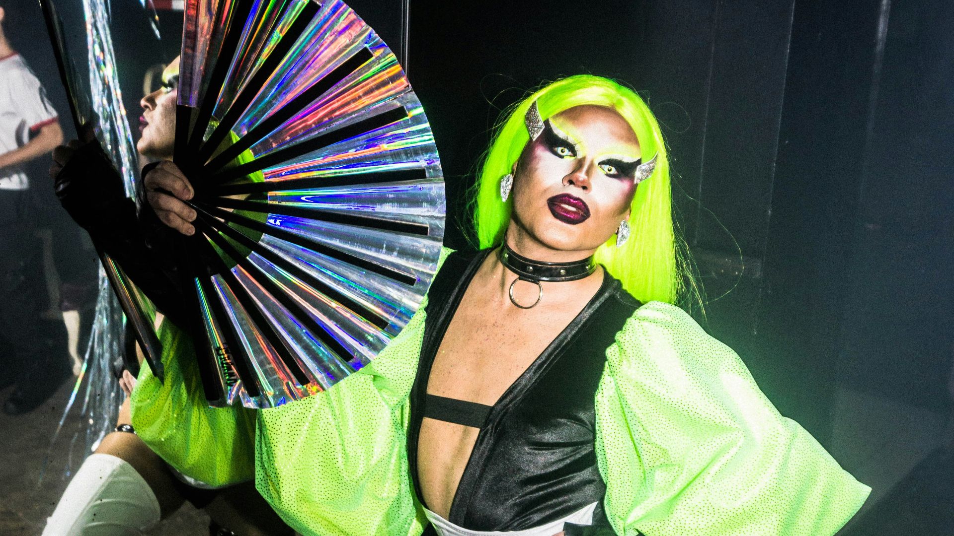 A drag queen poses with a fan.