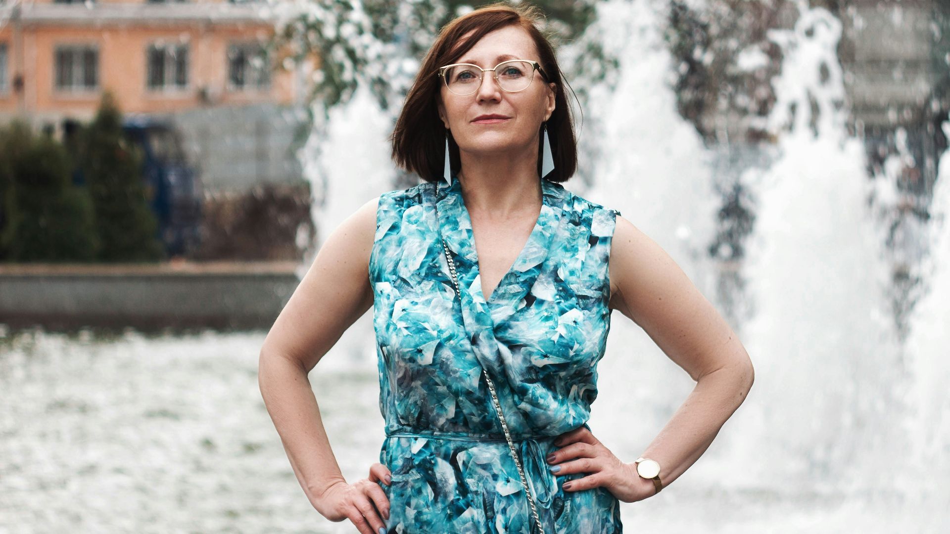 woman in blue and white floral sleeveless dress standing on snow covered ground during daytime