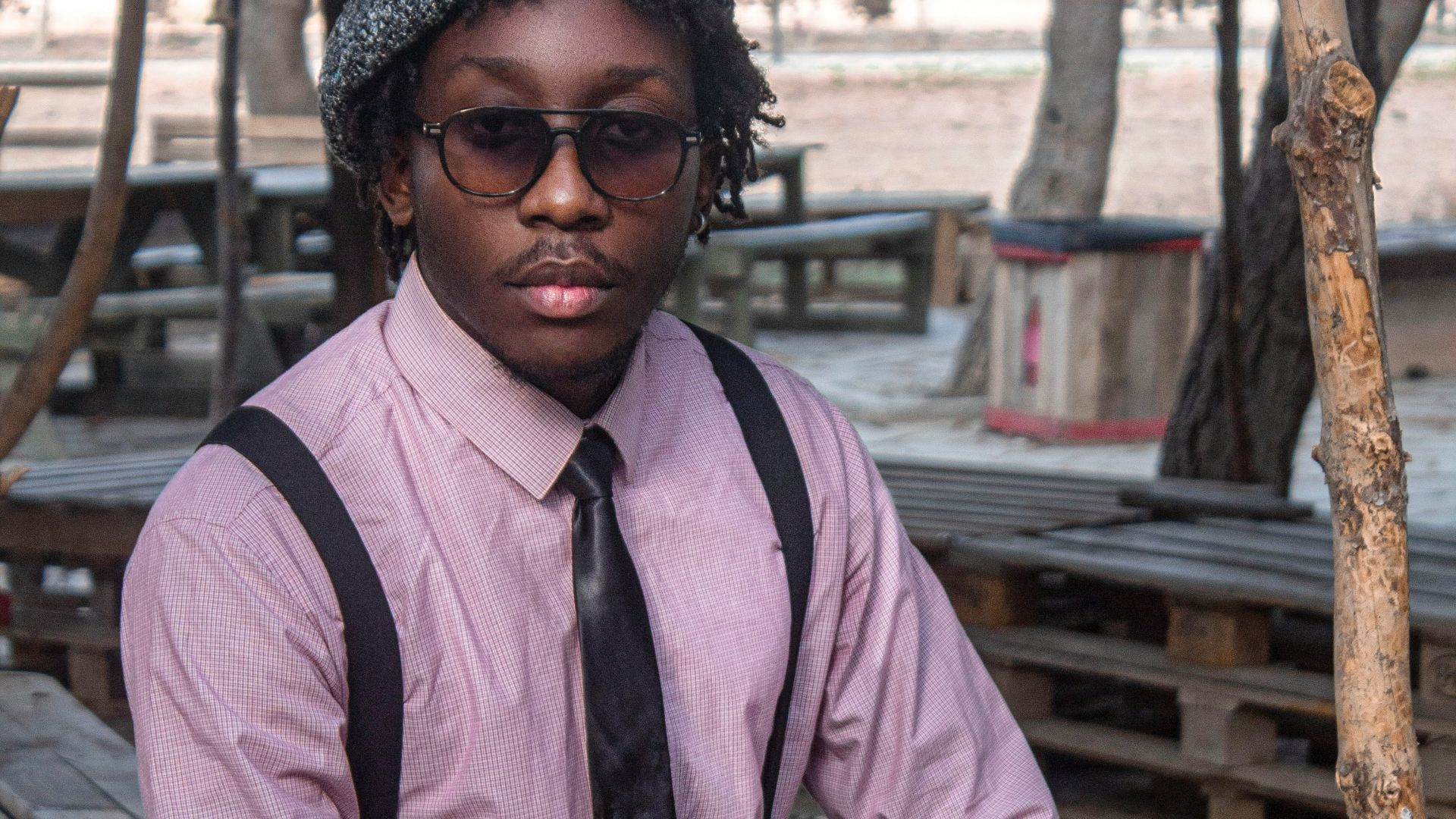 Young man in stylish outfit sitting outdoors
