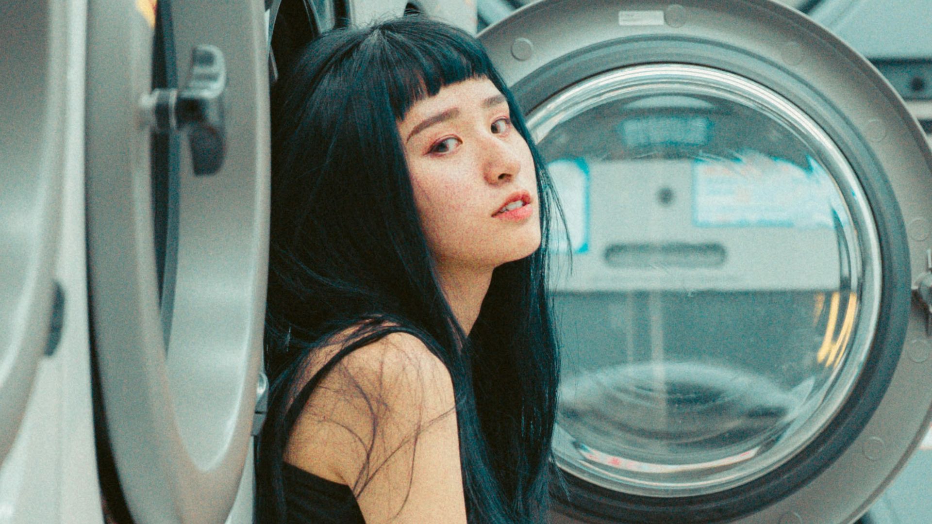 a woman sitting in front of a stack of washers