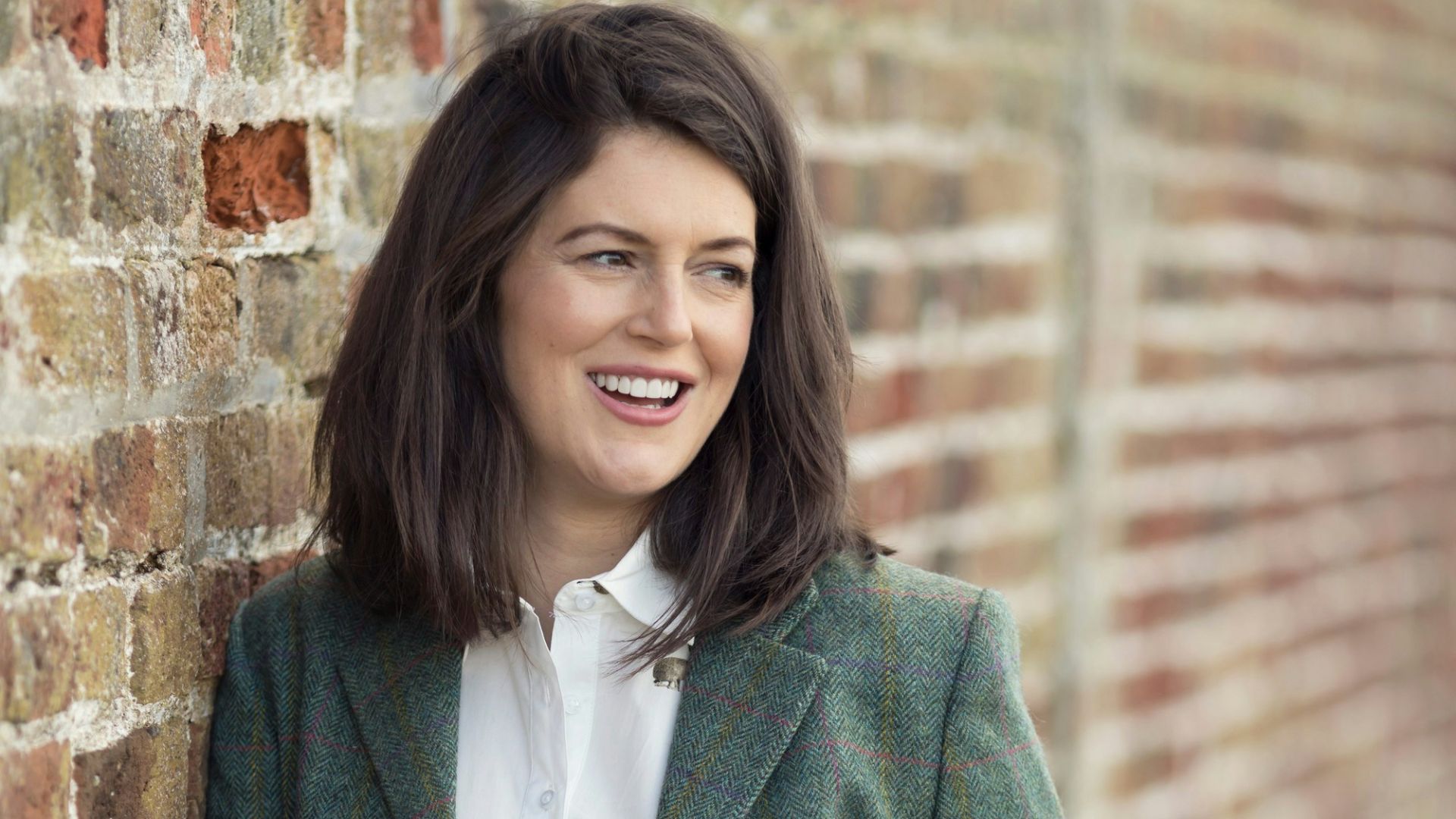 a woman leaning against a brick wall