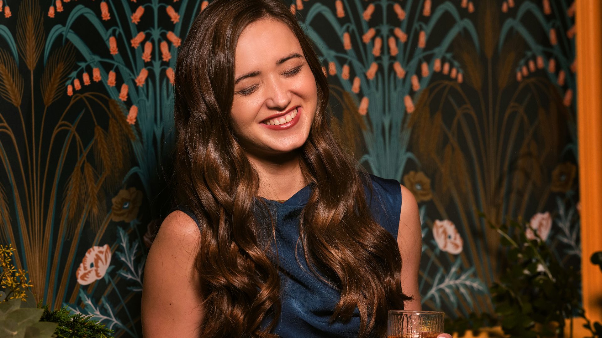 a woman in a blue dress holding a glass of wine