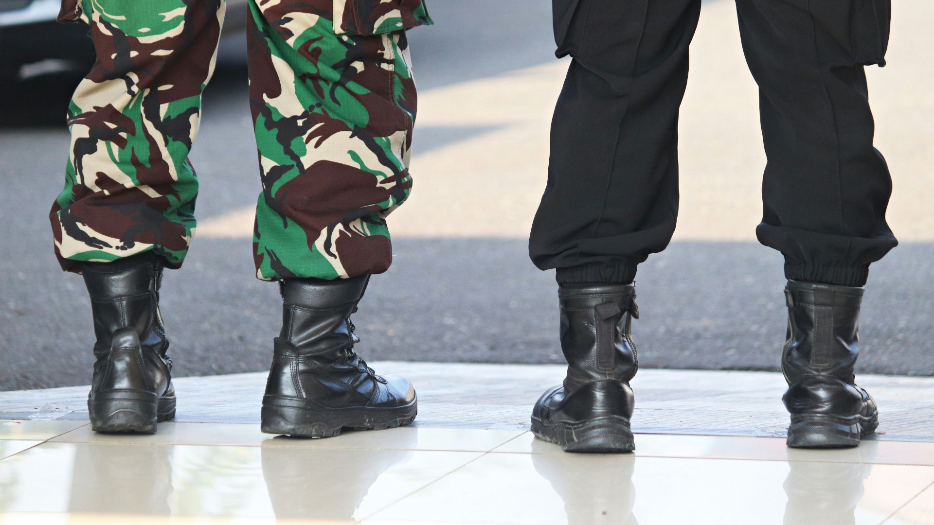 two people in camouflage pants and black boots standing next to each other