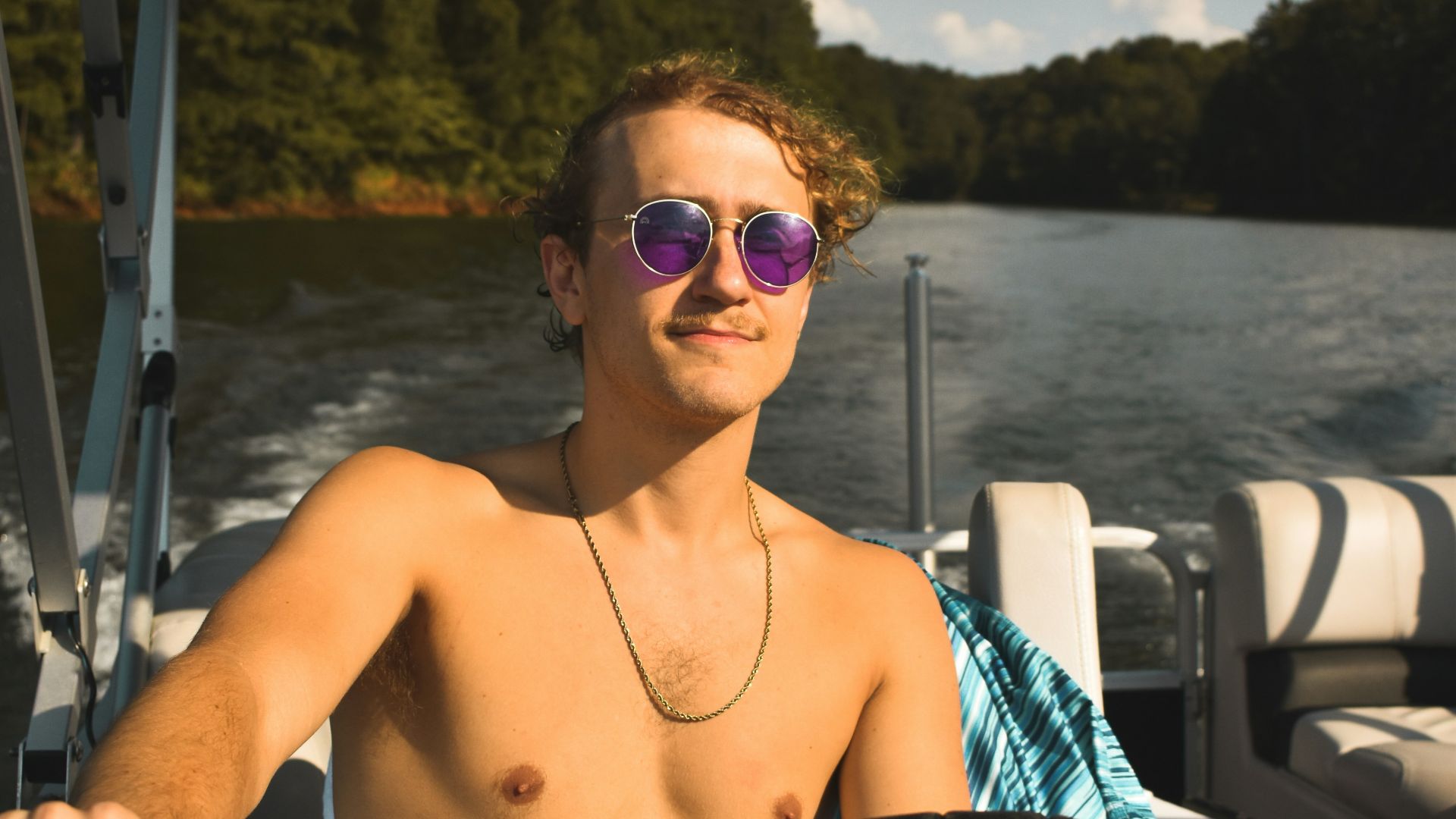 a shirtless man driving a boat on a lake