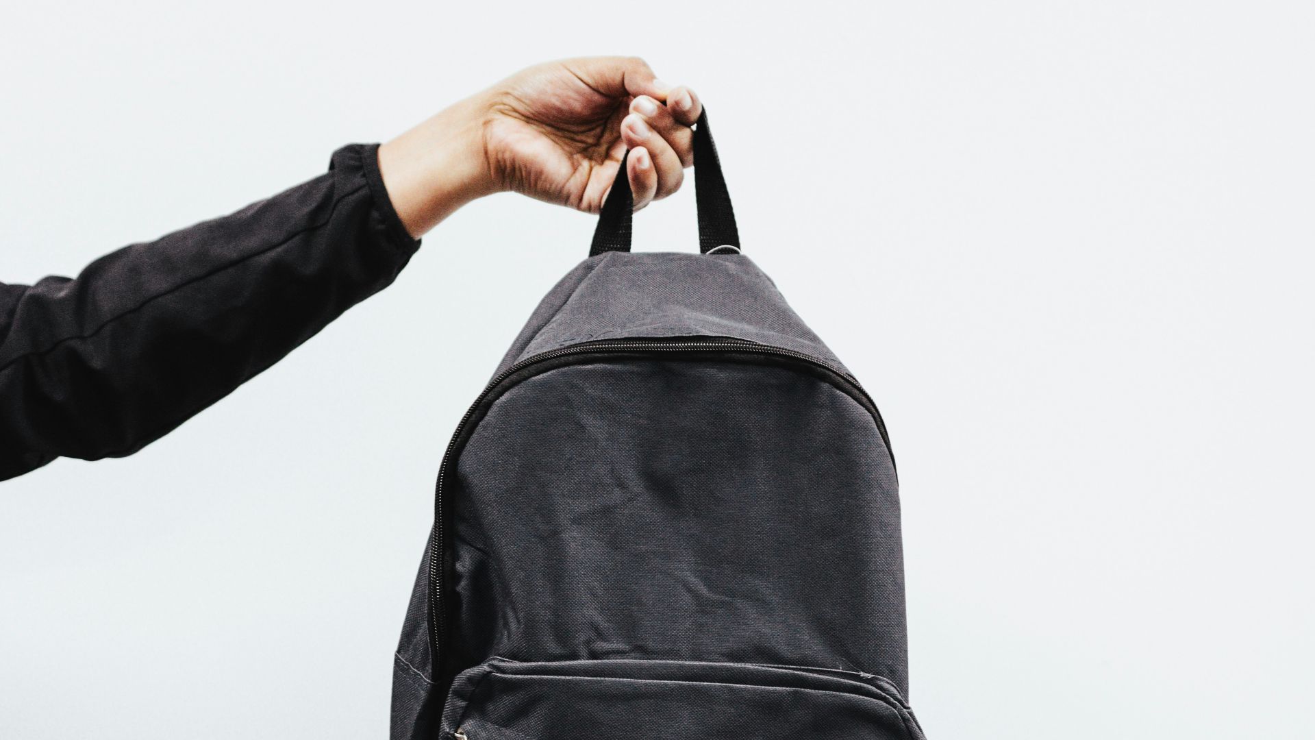 person in black jacket holding black backpack