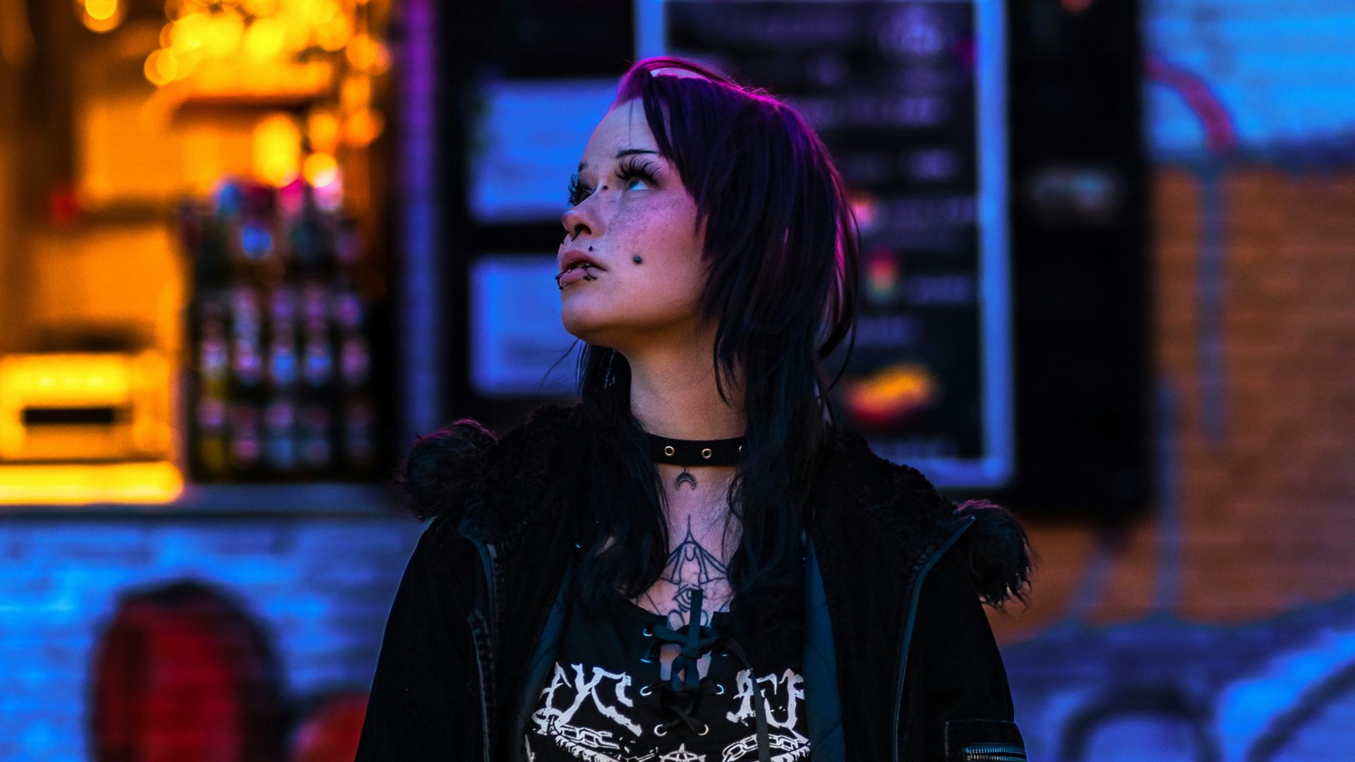 Woman with dark hair in edgy outfit under neon lights