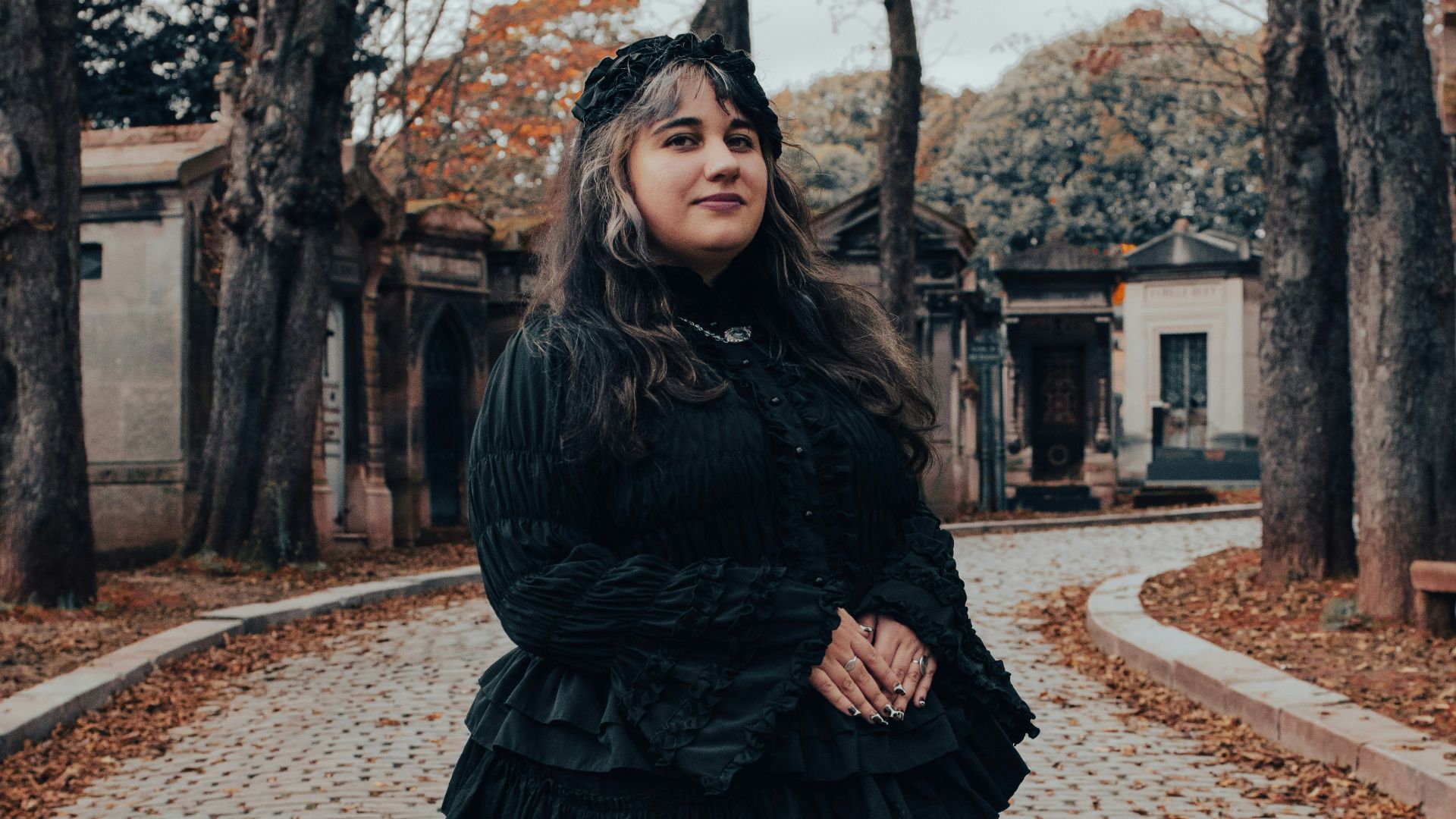 A woman in a black dress standing on a brick road