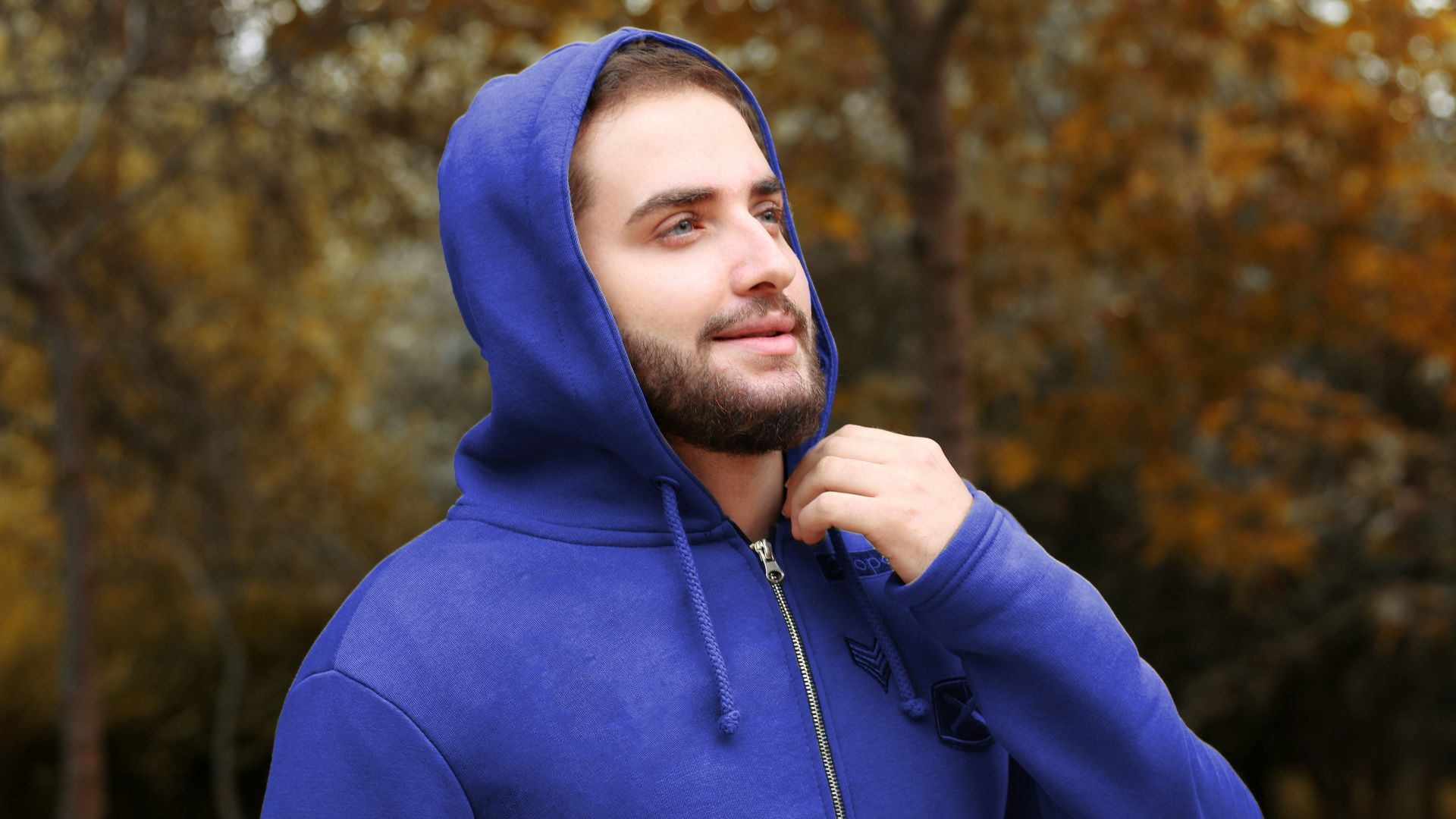 man in blue hoodie standing near trees during daytime
