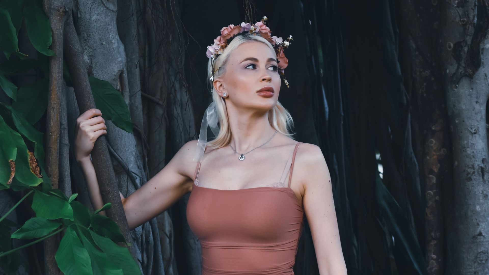 a woman in a dress standing in front of a tree