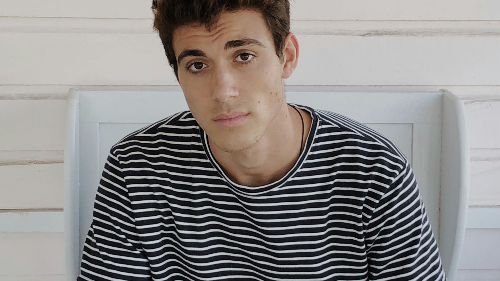 man in black and white striped crew neck t-shirt sitting on white plastic chair