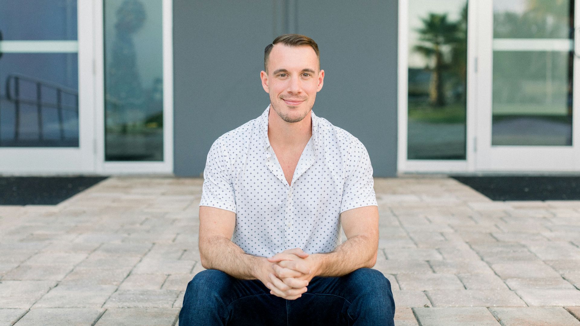a man sitting on the ground in front of a building