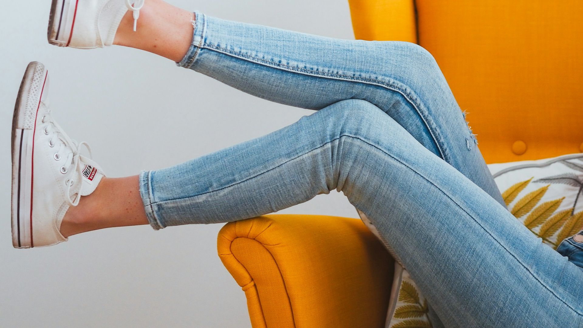 woman in blue denim jeans and white converse all star high top sneakers sitting on orange